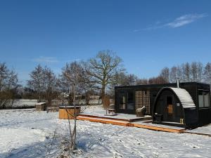 a small black building in a snow covered field at Het Kleine Genoegen in Heelweg