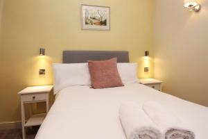 a bedroom with a white bed with two night stands at St John's Hill Apartments in Shrewsbury