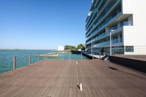 a wooden pier next to a large building next to the water at Tudor S Residence Mamaia in Văleni