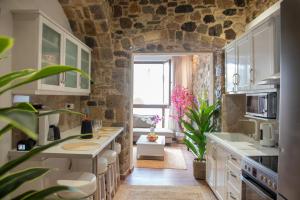 a kitchen with white cabinets and a stone wall at Kos View City , Luxury Old Town in Kos