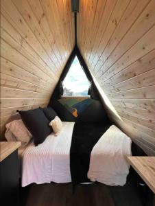 a bed in a room with a wooden wall at NEW! Unique Modern Glamping Chalet #5 in Orderville