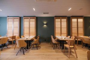 a dining room with tables and chairs and windows at Mondragon Hotela in Mondragón