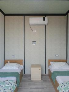 a room with two beds and a air conditioner at Aydarkul Beach in Taldy