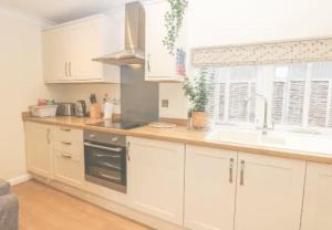 a kitchen with white cabinets and a sink and a window at Walworth Castle Cottage in Darlington