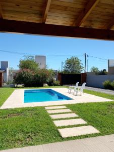 a swimming pool with two white chairs next to it at La Matera de Hugo in Lobos