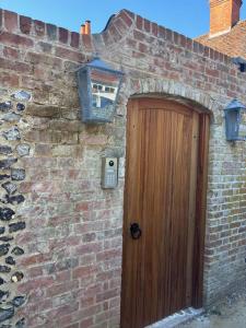 a brick building with a wooden door and a window at Pool House at Mill Cottage in Goring