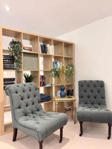 two chairs in a living room with a book shelf at The Baydon House Luxury Studio in Marlborough