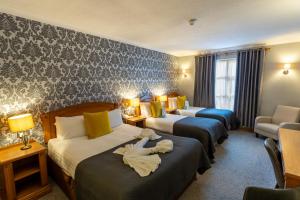 a hotel room with three beds in a room at Majestic Hotel in Tramore
