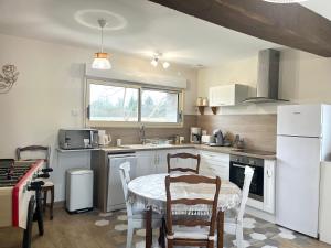 a kitchen with a table and a white refrigerator at La Maison Agoméa in Saint-Georges-sur-Cher