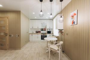 a kitchen with white cabinets and a table and chairs at Apart Center in Sumy