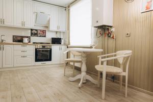 a kitchen with white cabinets and a table and chairs at Apart Center in Sumy
