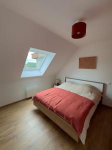 a bedroom with a bed with a red blanket at La maison des étangs in Rebecques