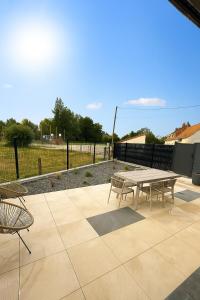 a patio with a table and chairs and a fence at La maison des étangs in Rebecques +2 photos