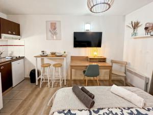 a room with a kitchen and a table with a bed at Le Cosy Saint-Cyr in Saint-Cyr-lʼÉcole