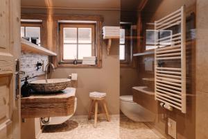 two images of a bathroom with a sink and a toilet at Alpenchalet Reit im Winkl in Reit im Winkl +65 photos