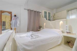 a white bedroom with a bed and a mirror at Debbie's Apartments in Adamantas