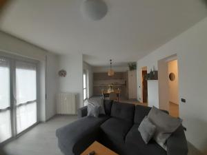 a living room with a black couch and a kitchen at Casa Vacanza dei Nonni in Varzo
