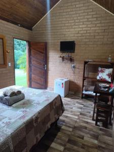 a bedroom with a bed and a tv on a brick wall at Chalés Beira Rio in Santo Antônio do Pinhal