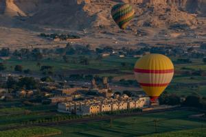 two hot air balloons are flying over a village at Yellow House on the Nile in Luxor