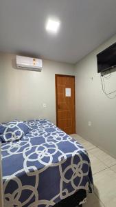 a bedroom with a bed with a blue and white comforter at Pousada Rafael in Juazeiro do Norte