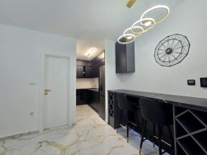 a kitchen with a bar with black chairs and a chandelier at Splendida in Bosanska Gradiška
