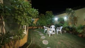 a patio with white chairs and plants at night at Four Squares by WIH in Karachi