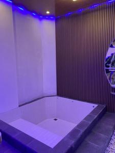 a white tub in a room with purple lights at HOUSEBOAT AFFA grup in Karanganyar