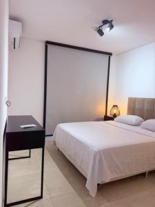 a bedroom with a white bed and a desk and a window at Feel Premiun 1203 in Asunción +18 photos