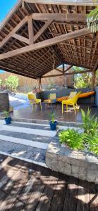 a patio with chairs and tables under a wooden pergola at Villa Ulutawu in Le François