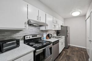 a kitchen with white cabinets and a stove top oven at Cozy Downtown Stone Mountain Apartment in Stone Mountain