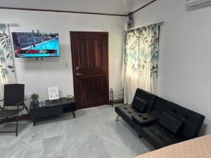 a living room with a black couch and a tv at Virginia's apartaments in Omoa +3 photos