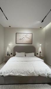 a bedroom with a large white bed with two lamps at ZA apartment in Al Ahsa