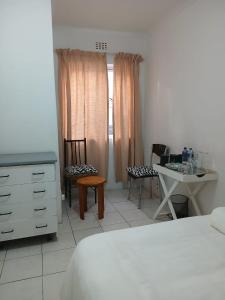 a bedroom with a bed and a table and chairs at DigiStay in Simonʼs Town
