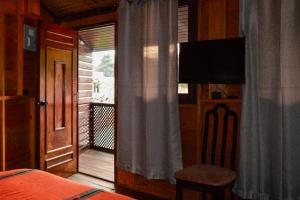 a bedroom with a bed and a television and a window at El Refugio - Hospedaje y Eventos in San Lucas Sacatepéquez