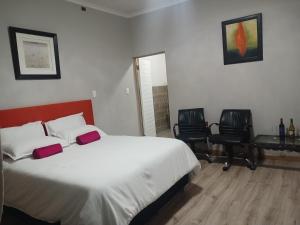 a bedroom with a bed and two chairs and a desk at Donido's Place in Alberton