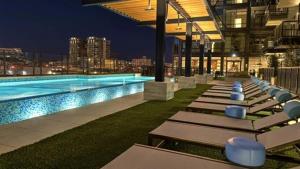 a row of lounge chairs next to a swimming pool at night at Deep Ellum Lux in Dallas