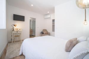 a white bedroom with a bed and a desk at Portas da Villa in Miranda do Douro