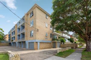 an apartment building with a tree in front of it at Shoreleaf Haven - Moments from Waves & Seaside Eats in Deewhy