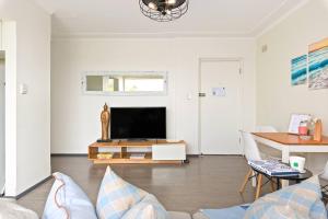 a living room with a television and a table at Shoreleaf Haven - Moments from Waves & Seaside Eats in Deewhy