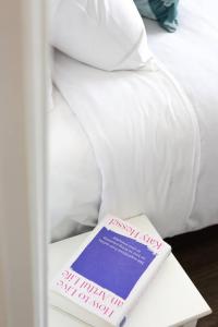a book sitting on a table next to a bed at Shoreleaf Haven - Moments from Waves & Seaside Eats in Deewhy