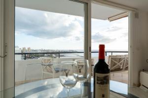 a bottle of wine and two glasses on a table on a balcony at Club Villamar Exclusive Beachfront Penthouse in Adeje