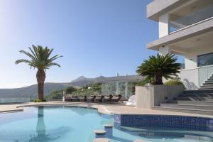a swimming pool in front of a building with palm trees at Villa Kalliston - 4000m2 of Elevated Living in Rethymno