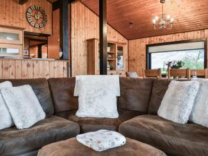 a living room with a brown couch and a clock at Glendowlin Lodge Retreat in Tirril