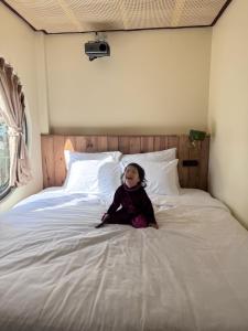 a little girl sitting on a bed at The Hue Verandah in Thôn Trường Giang