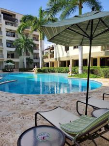 a couple of chairs and an umbrella next to a swimming pool at PALMARUBA 2bedroom condo in Palm-Eagle Beach