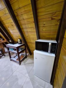 a microwave on top of a refrigerator next to a table at Chalé a 500 metros do Pico Malwee in Jaraguá do Sul