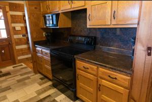a kitchen with wooden cabinets and a black stove top oven at Governor's Private Cabin on Bourbon Trail w HotTub in Harrodsburg