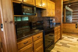 a kitchen with wooden cabinets and a stove top oven at Governor's Private Cabin on Bourbon Trail w HotTub in Harrodsburg