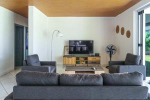 a living room with a couch and a tv at 3BR Beachfront Villa Steps from the Lagoon in Paopao