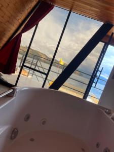 a bath tub in a bathroom with a large window at Lago de Tota GALAMPLAY lodge in Tota